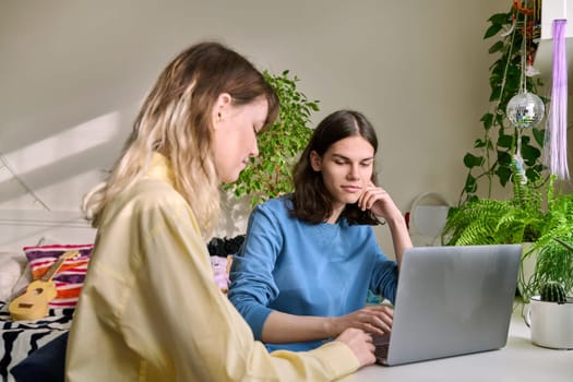 Teenage friends male and female using laptop at home for leisure. Youth, lifestyle, communication, friendship, technology, young people concept