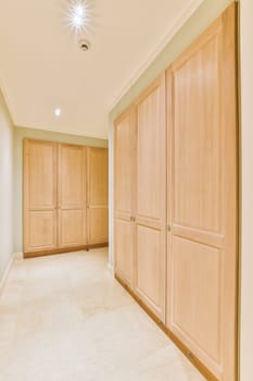 an empty room with wooden cabinets and white marble flooring in the room is well lit by recessed light