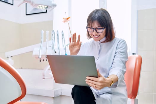 Online consultation, doctor help in clinic using laptop. Female dentist talking looking in laptop in dental office. Video conference, videocall, service, dentistry, medicine, technology concept