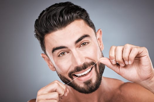 Dental floss, teeth and portrait of man in studio for beauty, healthy body and hygiene on background. Male model, tooth flossing and cleaning mouth for facial smile, fresh breath and happy cosmetics.