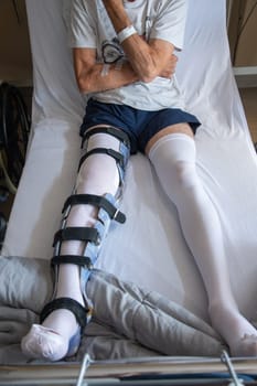 a man with a broken leg in an orthese in bed in a clinic after an accident, High quality photo