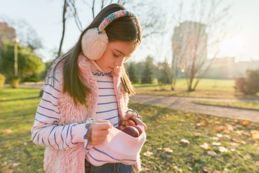 Harvesting, little beautiful girl with apples in autumn park, golden hour copy space