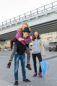 Teens boy and two girls talking and having fun outdoor, lifestyle of teenagers in the city