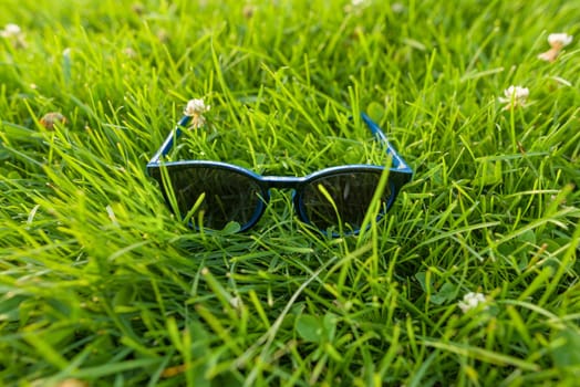 Sunglasses in bright green grass, summer accessory.