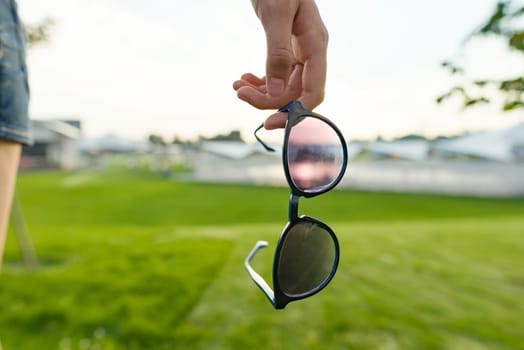 Sunglasses symbol of summer, background horizon with sunset, green lawn.