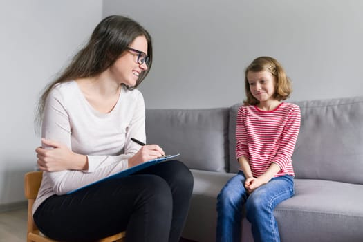 Professional child psychologist talking with child girl in office, children problems, mental professional help