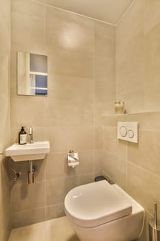 a toilet and sink in a small bathroom with beige tiles on the walls, along with a wall mounted mirror