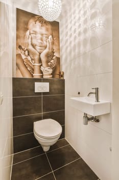 an elephant on the wall next to a toilet in a white tiled bathroom with black tile flooring and walls