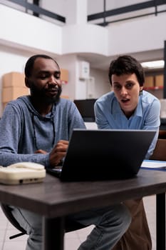 Manager and supervisor looking at transportation logistics on laptop computer searching for online orders while working in warehouse. Concept of heavy industry manufacturing factory.