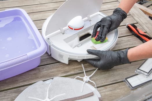 woman washing a trash can in a robot vacuum cleaner,planned maintenance of equipment for long-term use, High quality photo