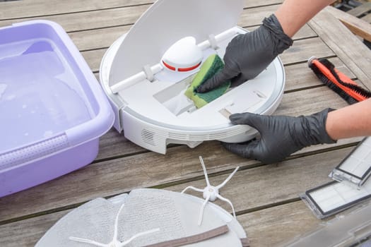 woman washing a trash can in a robot vacuum cleaner,planned maintenance of equipment for long-term use, High quality photo