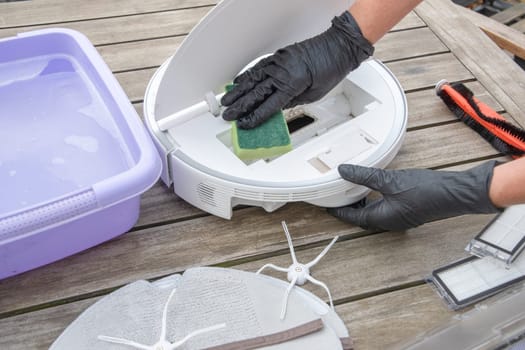 woman washing a trash can in a robot vacuum cleaner,planned maintenance of equipment for long-term use, High quality photo