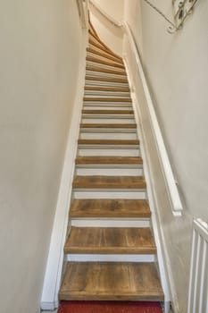 some wooden stairs in a white wall and red carpet on the floor, with an open door leading to another room