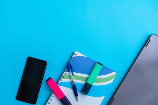 Several highlighter with a notebook next to a laptop and phone.