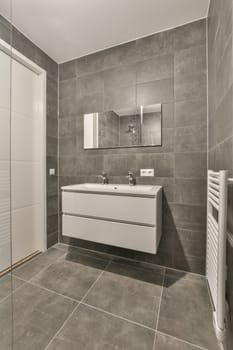 a modern bathroom with grey tiles and white fixtures on the walls, along with a large mirror in the corner