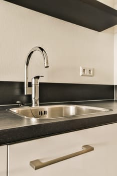 a kitchen with black and white tiles on the wall behind it is a sink, fauced in front