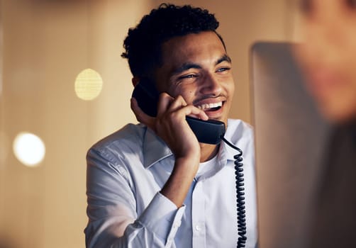 Telephone, night and businessman on a phone call in the office talking while working on a computer. Discussion, communication and professional male employee speaking on a landline in the workplace