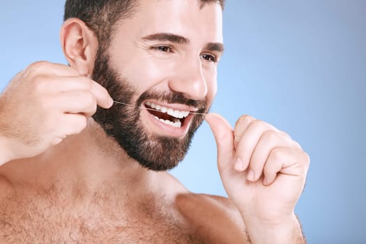 Dental, product or floss with a man in studio on a blue background with teeth hygiene for healthy gums. Dentist, healthcare and mouth with a young male oral cleaning to remove plague or gingivitis.