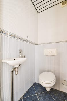 a bathroom with white tile and blue tiles on the floor, along with a toilet in the corner of the room