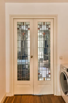 the inside of a house with two doors and a washer in front of it on a hardwood wood floor