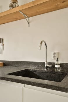 a kitchen sink and faucet in a white room with black granite countertops on the wall above it