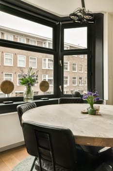 a dining table and chairs in front of a large window looking out at the city outside with flowers on it