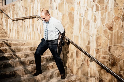 Portrait of a senior professional man in a suit with various problems. A middle-aged businessman with a briefcase descends the stairs.