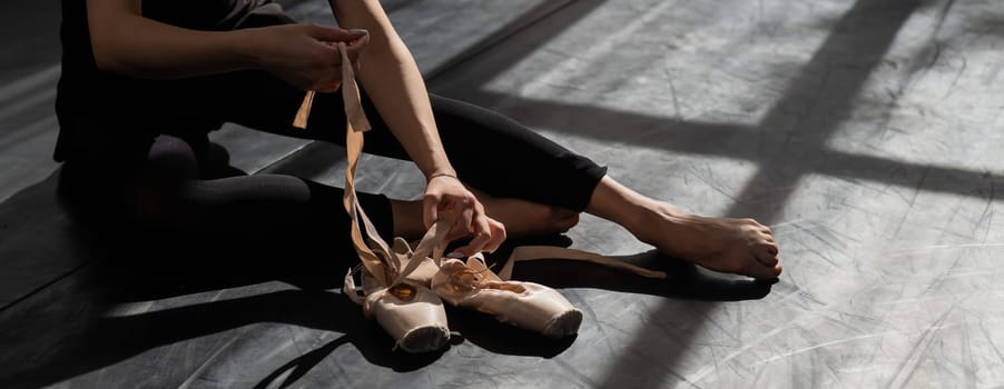 Faceless ballerina sits on the floor and puts on pointe shoes. Widescreen