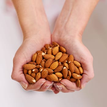 The nutty health solution. a bunch of almonds in a persons cupped hands