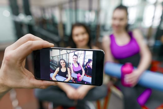 Young athletic smiling woman laughing in the gym, photographed on mobile phone. Fitness, sport, training, people, healthy lifestyle concept