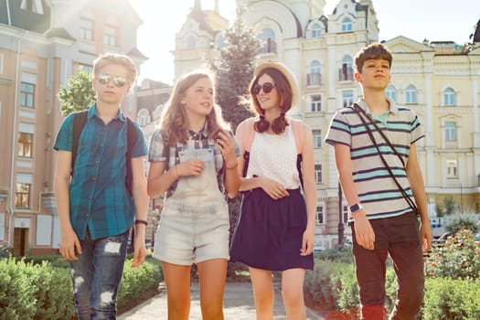 Group of happy smiling talking friends teenagers, young people walking in the city on sunny summer evening. Friendship and people concept.