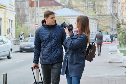 Young positive couple of young men and women blogger in city with camera. Travel, city blogging.