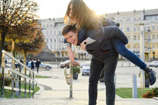 Couple of beautiful students are having fun in city, background spring city, young man and woman laughing, golden hour.