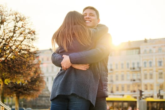 Young beautiful couple is embracing and having fun, romance in the spring city, golden hour.