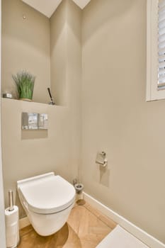 a small bathroom with a toilet and plant on the wall in front of the toilet is an empty white room