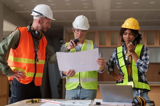 Architect team working with blueprints for architectural plan, engineer sketching a construction project, green energy concept.