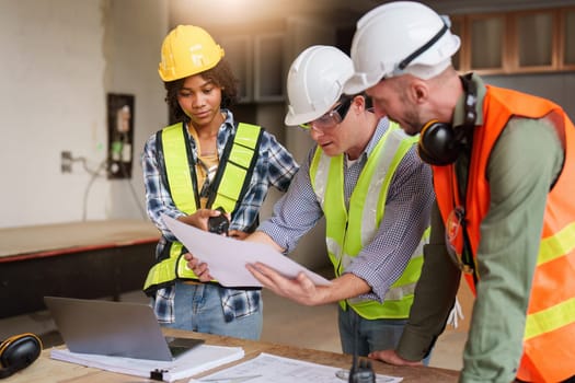 Architect team working with blueprints for architectural plan, engineer sketching a construction project, green energy concept.