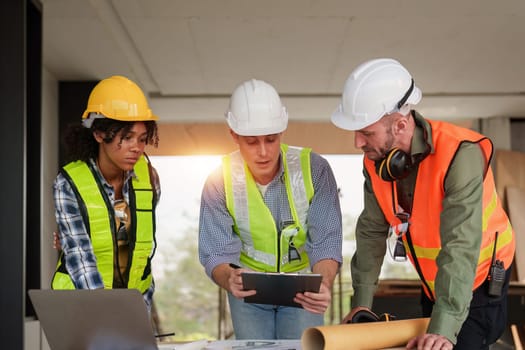 Architect team working with blueprints for architectural plan, engineer sketching a construction project, green energy concept.