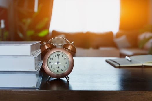 desk clock and books on wooden table.