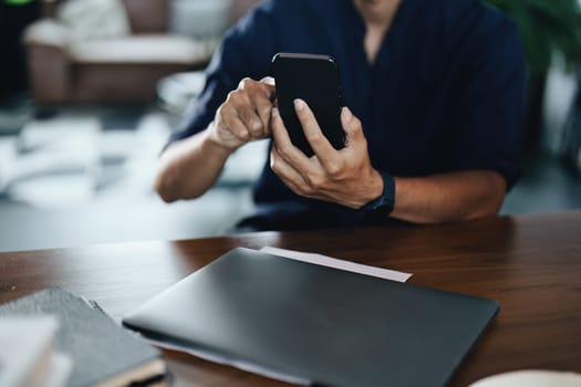 Asian man at his desk and on the phone.