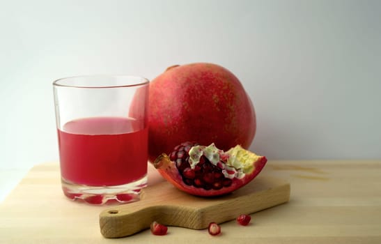 Pomegranate and pomegranate juice, photo. Photo of pomegranate and pomegranate juice in a glass on a wooden board.
