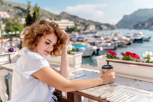 Happy beautiful woman drinking coffee with milk and having healthy breakfast in outdoor cafe in summer city in Europe