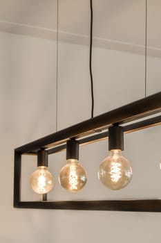 some light bulbs hanging from a beam in a room with white walls and wood flooring on the wall behind them