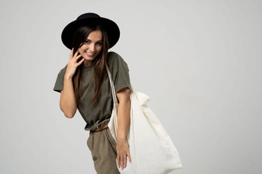Happy beautiful brunette woman with white cotton bag in her hands. Girl holding textile grocery bag with vegetables. Zero waste concept