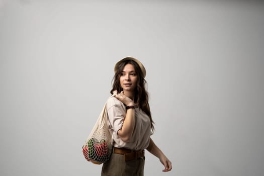 Young woman holding mesh grocery bag with vegetables Concept of no plastic. Zero waste, plastic free. Eco friendly concept. Sustainable lifestyle