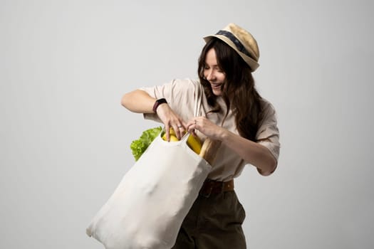 Woman holding textile grocery bag with vegetables. Zero waste concept. Package-free food shopping. Eco friendly natural bag with organic fruits and vegetables