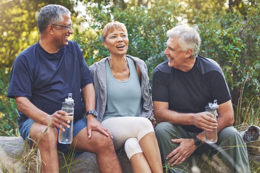 Nature, fitness and senior friends in conversation while sitting in the forest after hiking. Happiness, communication and elderly people talking, bonding and drinking water after outdoor exercise