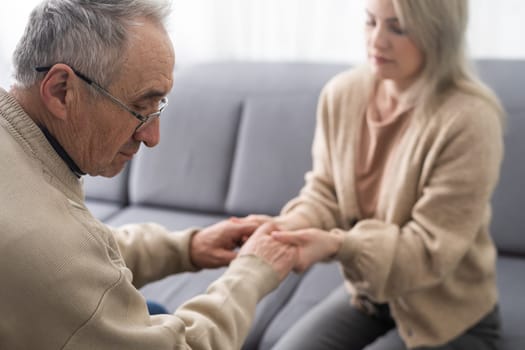 Nurse holding hand of senior man in rest home.