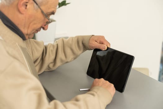 Senior man using tablet computer at home in the living room