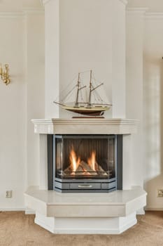 a living room with a fire in the fireplace and a ship model on top of the fireplace mantels